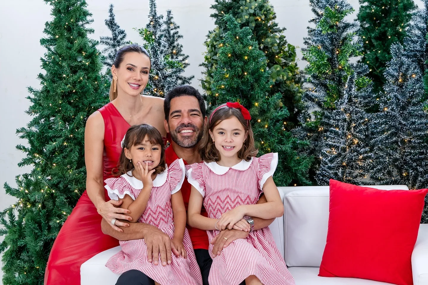 Família em retrato com cenário natalino e árvores ao fundo