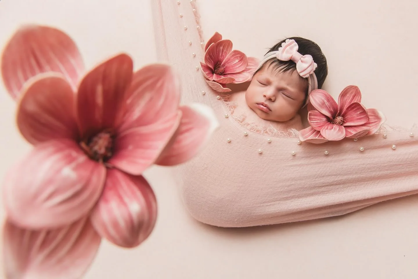 Recém-nascido em uma composição delicada com flores em tons de rosa
